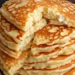 Flourless cottage cheese pancakes stacked on a plate with maple syrup and fresh berries